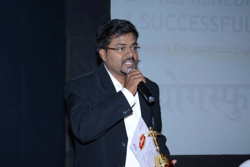 Pranjal Chawan speaking on stage holding a trophy